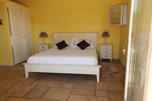 Une chambre à coucher avec un lit, deux tables de chevet, une armoire et un miroir au mur.