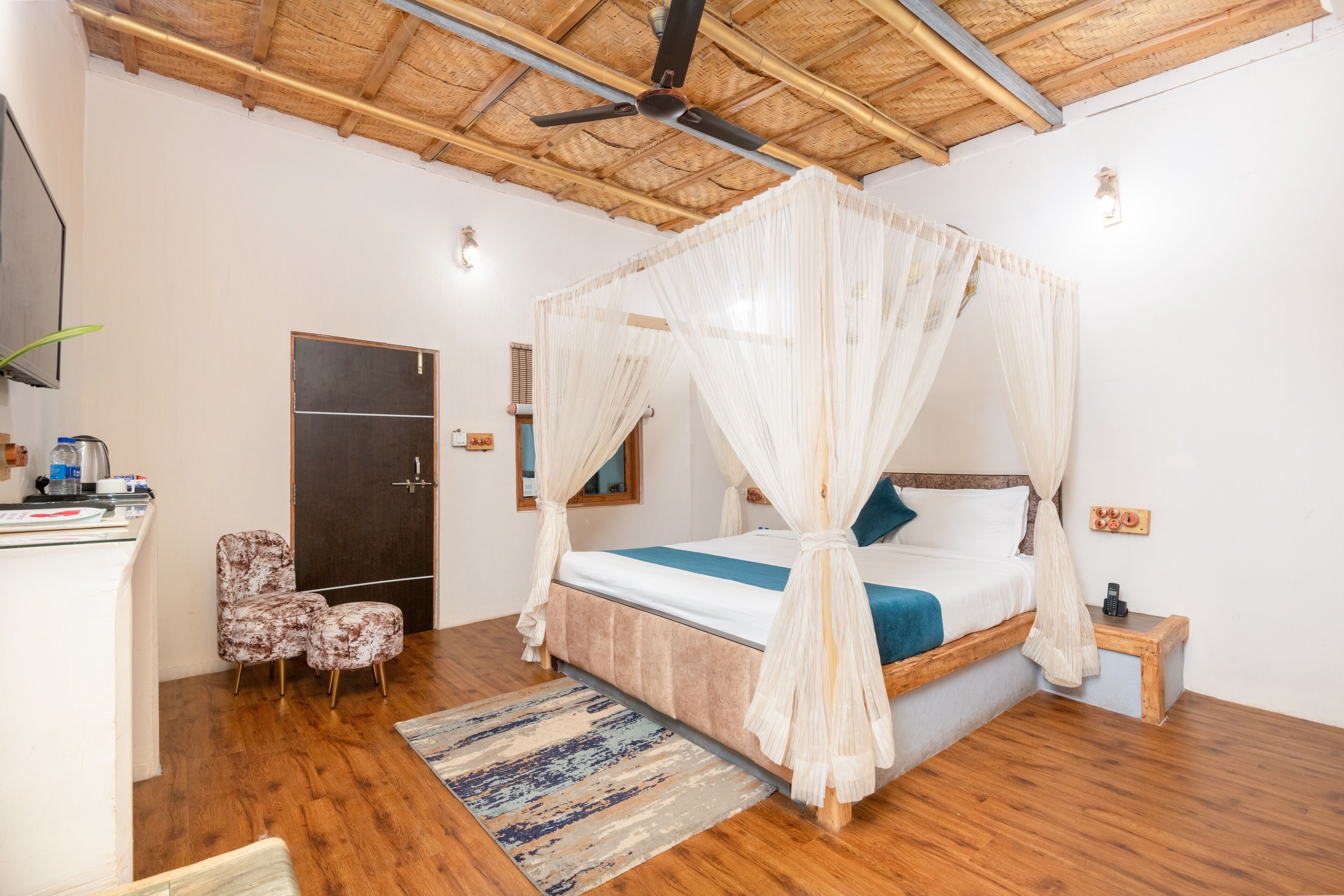 Une chambre à coucher avec un lit à baldaquin, un plancher en bois, un ventilateur de plafond et une petite table de chevet.