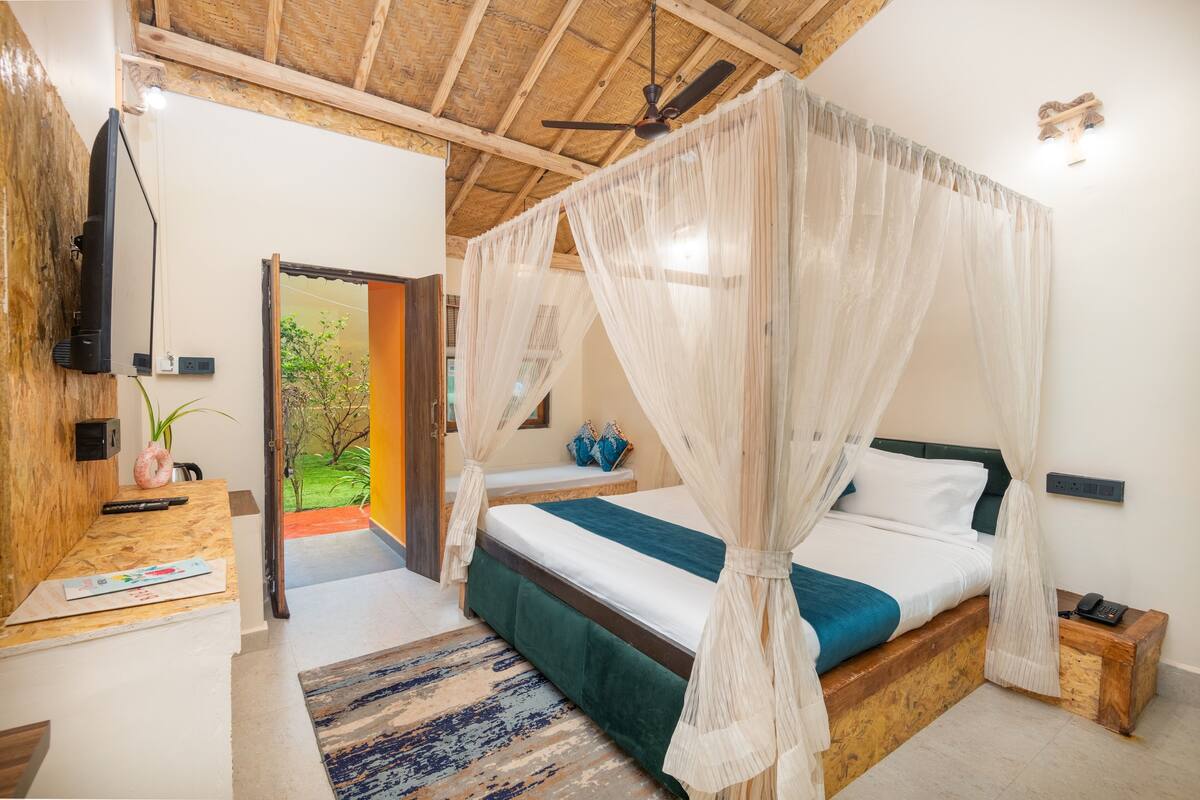 A room with a bed, a TV, a desk, and a door leading outside.