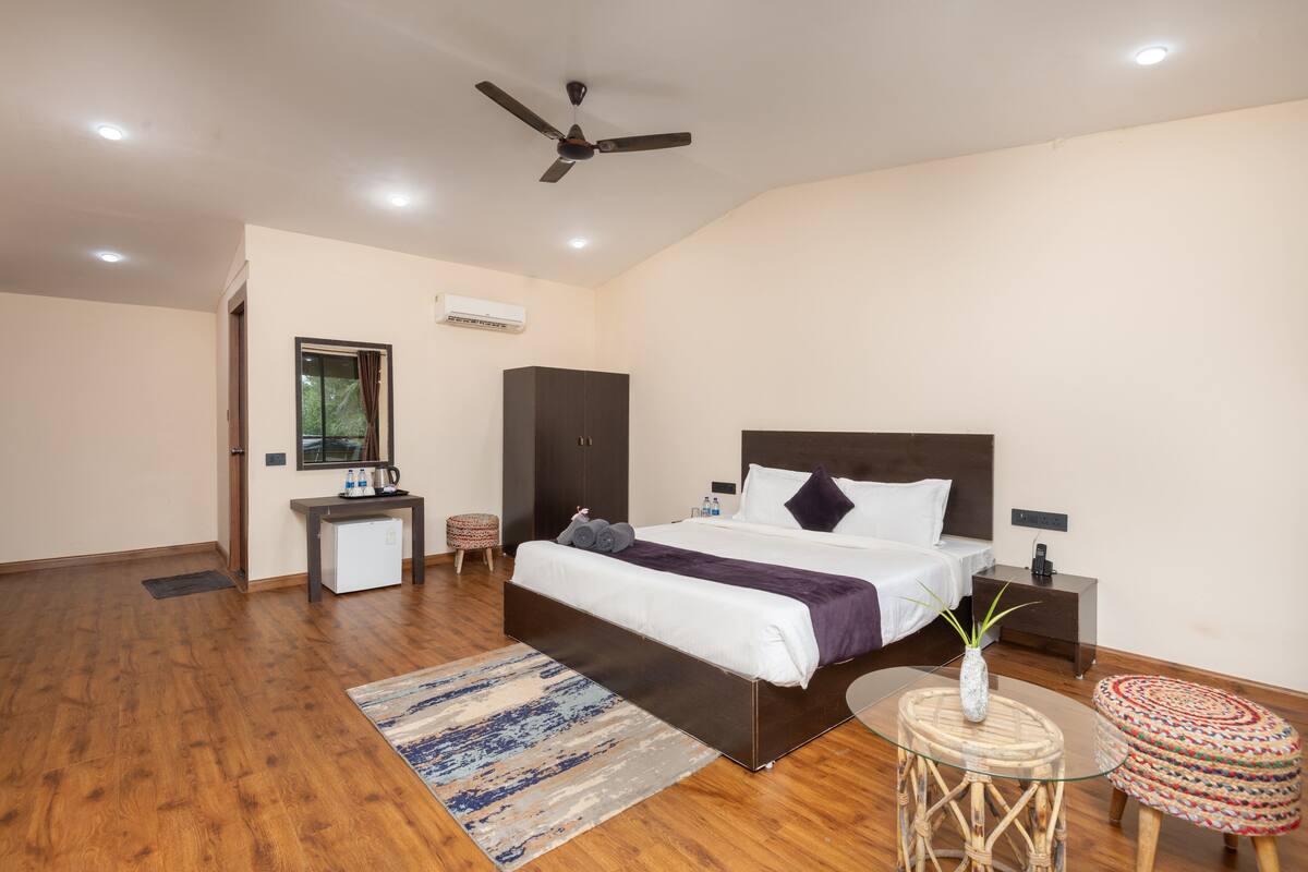 A bedroom with a large bed, bedside tables, a ceiling fan, and a small desk with a chair.