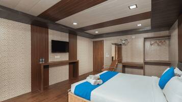 Un dormitorio con una cama de madera, un televisor montado, un espejo y un ventilador.