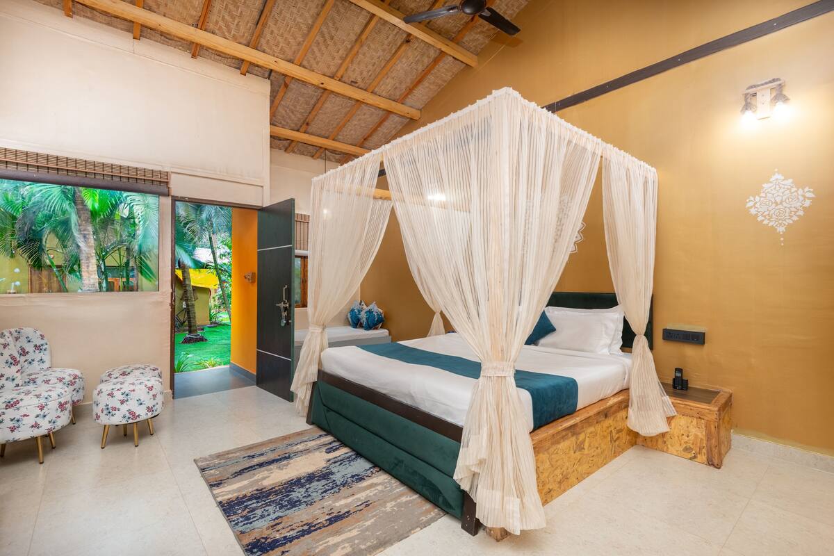 A bedroom with a four-poster bed, a wooden headboard, a nightstand, and a small table.