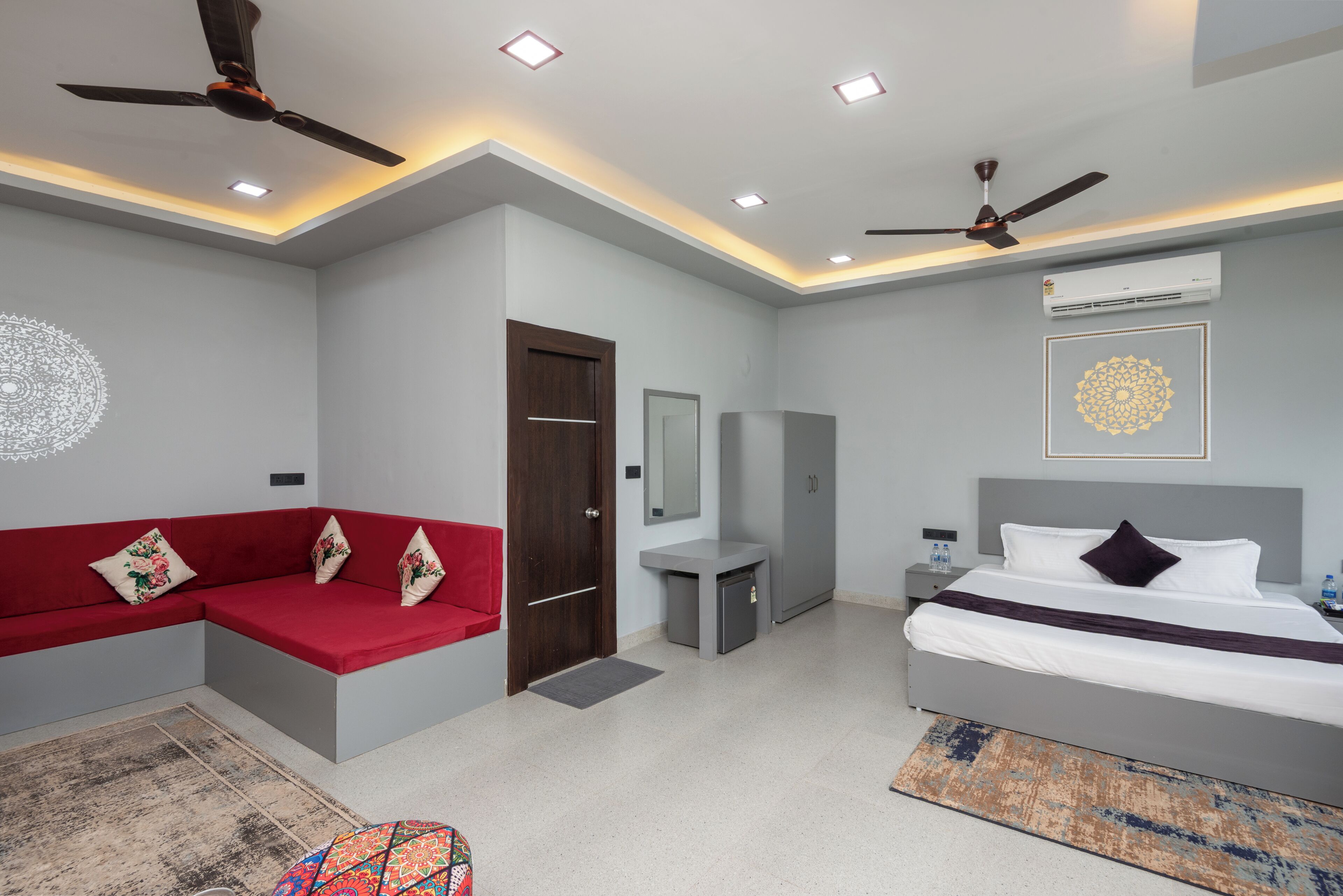 A modern bedroom with a bed, a red sofa, a ceiling fan, and a small bedside table.