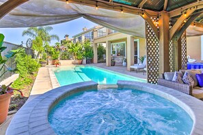 Ein Bereich mit Whirlpool und Pool, umgeben von Topfpflanzen und Gartenmöbeln.