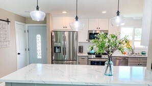 A modern kitchen with a marble island, stainless steel appliances, and pendant lighting. - Modern 4-beds House Near Disneyland & Knott's Berry Farm (Anaheim)