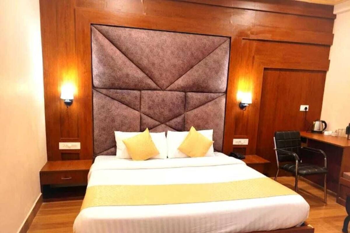 A hotel room with a large bed, two bedside tables, a desk, and a chair.