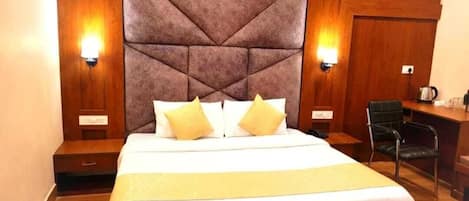 A hotel room with a large bed, two bedside tables, a desk, and a chair.