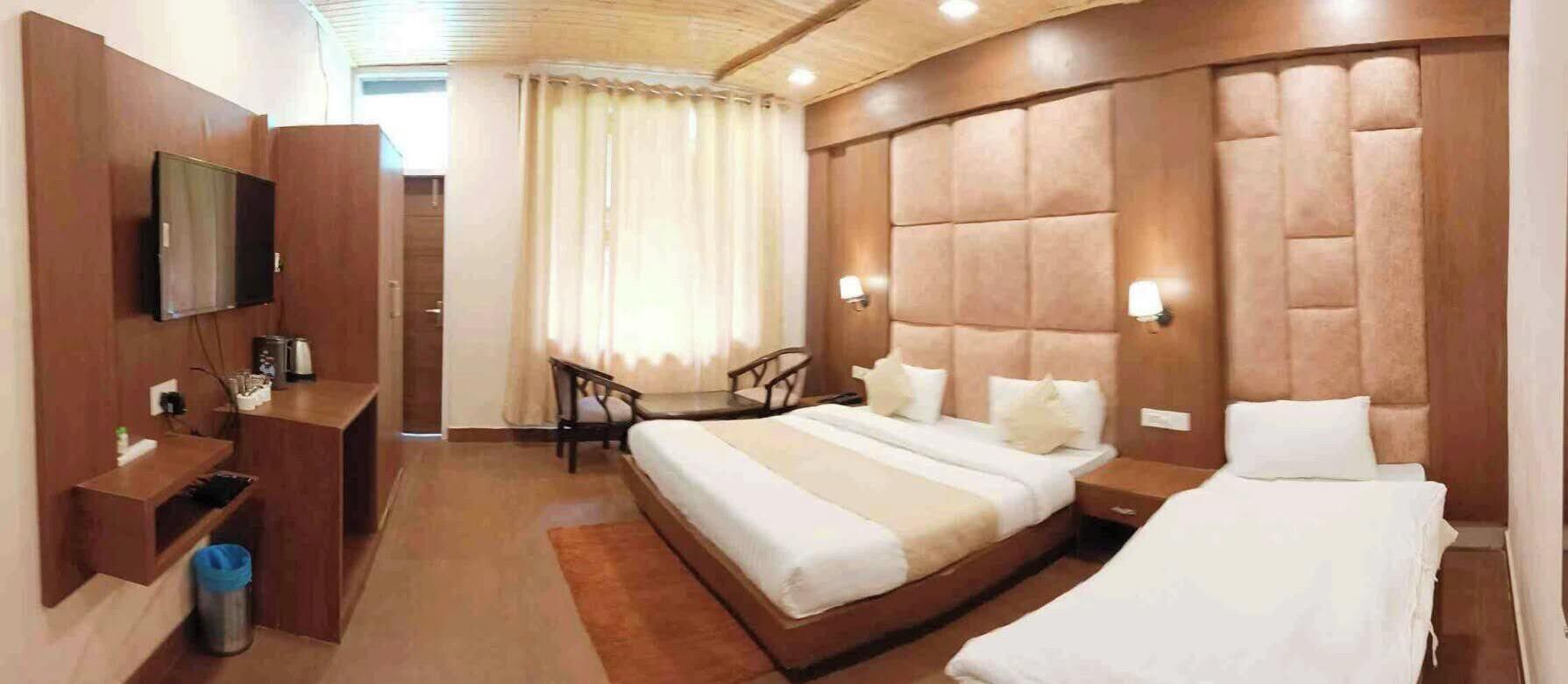 A hotel room with a large bed, a TV, a desk, and a chair.
