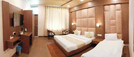 A hotel room with a large bed, a TV, a desk, and a chair.