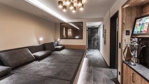 Un interno moderno con un divano, uno specchio, un angolo cottura dotato di elettrodomestici e un corridoio che conduce a un box doccia.