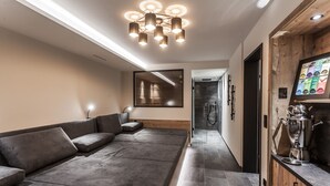 Een modern interieur met een bank, een spiegel, een keukenhoek met een koffieapparaat, en een douche.