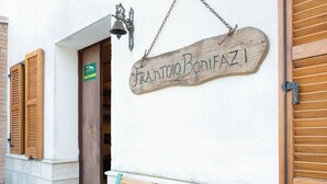 A wooden sign with the name "Frantoio Bonifazi" hanging on a white wall, a wooden door, and a bench outside. - Sun-kissed holiday home with swimming pool (Itieli)