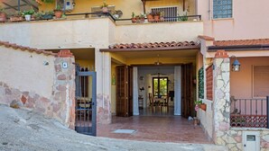 Un edificio de dos pisos con fachada de piedra, entrada de azulejos y un balcón con macetas.