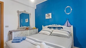 Un dormitorio con una cama grande, un tocador, un espejo y una pared azul decorativa.