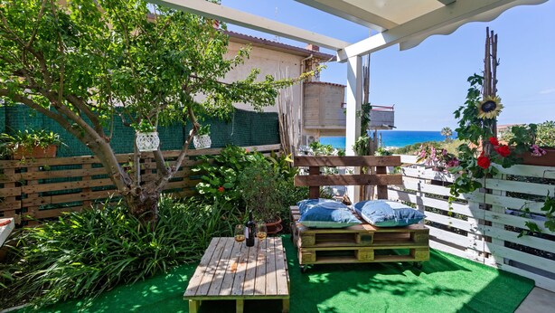Un patio con una mesa de madera, una banca y una planta en maceta.
