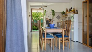 Un comedor con una mesa y sillas de madera, un tazón azul y un refrigerador.