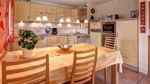 A modern kitchen with a dining area, featuring a central island, built-in appliances, and pendant lighting. - Katamaran II by Interhome (Burhave)