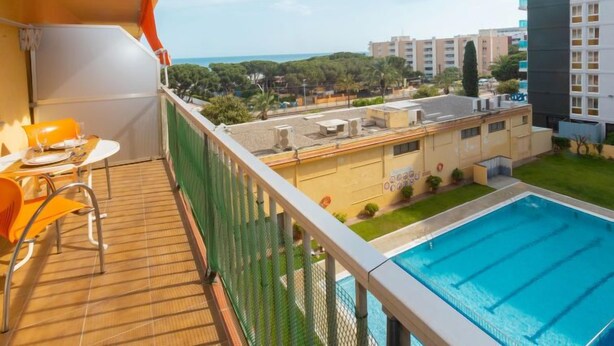 Un balcón con piscina, mobiliario exterior y vista a la ciudad.