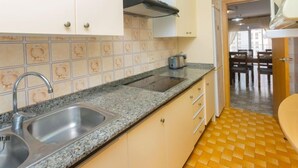 Una cocina con encimera de granito, pileta de acero inoxidable y salpicadero de azulejos.