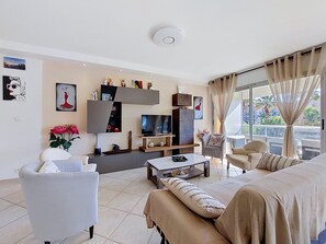 A modern living room with a sofa, armchair, coffee table, TV, and artwork on the walls.