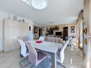 Uma sala de jantar moderna com uma mesa branca, cadeiras e um arranjo de tigela vermelha.