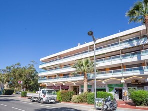 Un hôtel à plusieurs étages, doté de balcons, d’un parking et donnant sur la rue.