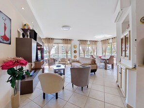 A spacious living area with a sofa, armchairs, a coffee table, and a TV.