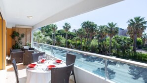 A balcony with a dining table set for four, overlooking a palm tree-lined street. - Les Palmiers by Interhome (Le Lavandou)