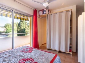 Une chambre à coucher avec un lit, une fenêtre donnant sur un beau paysage, un placard et un ventilateur de plafond.
