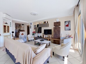 Uma sala de estar moderna com sofá, poltronas, mesa de centro, televisão e lareira.