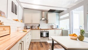 Une cuisine moderne avec des meubles blancs, un plan de travail en bois et une table à manger.