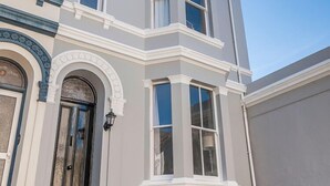 Un coin d’un bâtiment avec une baie vitrée et une porte surmontée d’un arc décoratif.