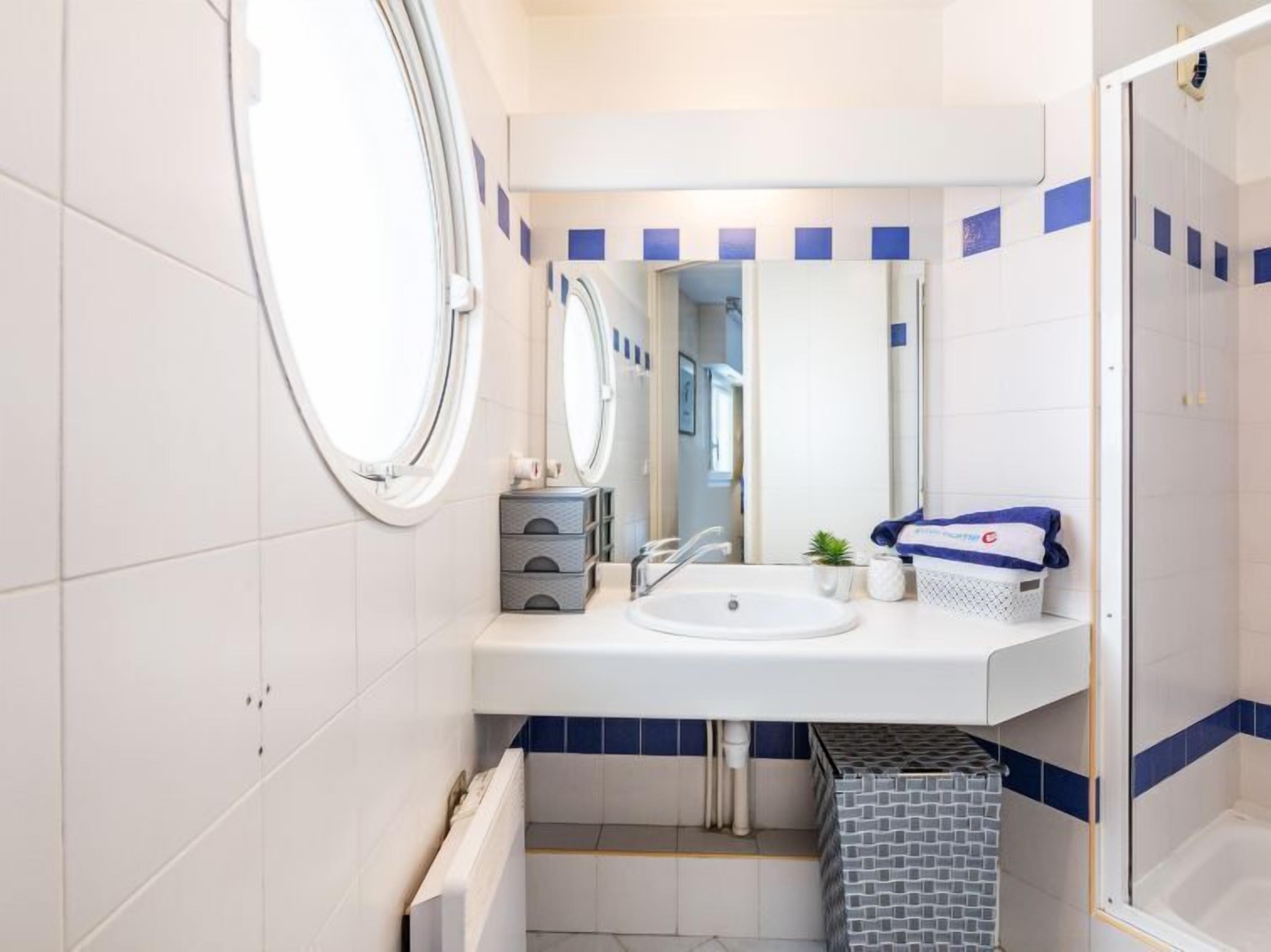 A modern bathroom with a round mirror, a sink, and a shower area.