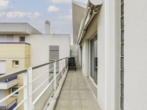 A narrow balcony with a metal railing, a tiled floor, and a view of adjacent buildings.