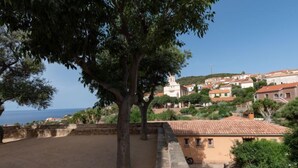 A courtyard with a stone wall, a tree, and a building with a tiled roof. - La Spelunca by Interhome (Cargèse)