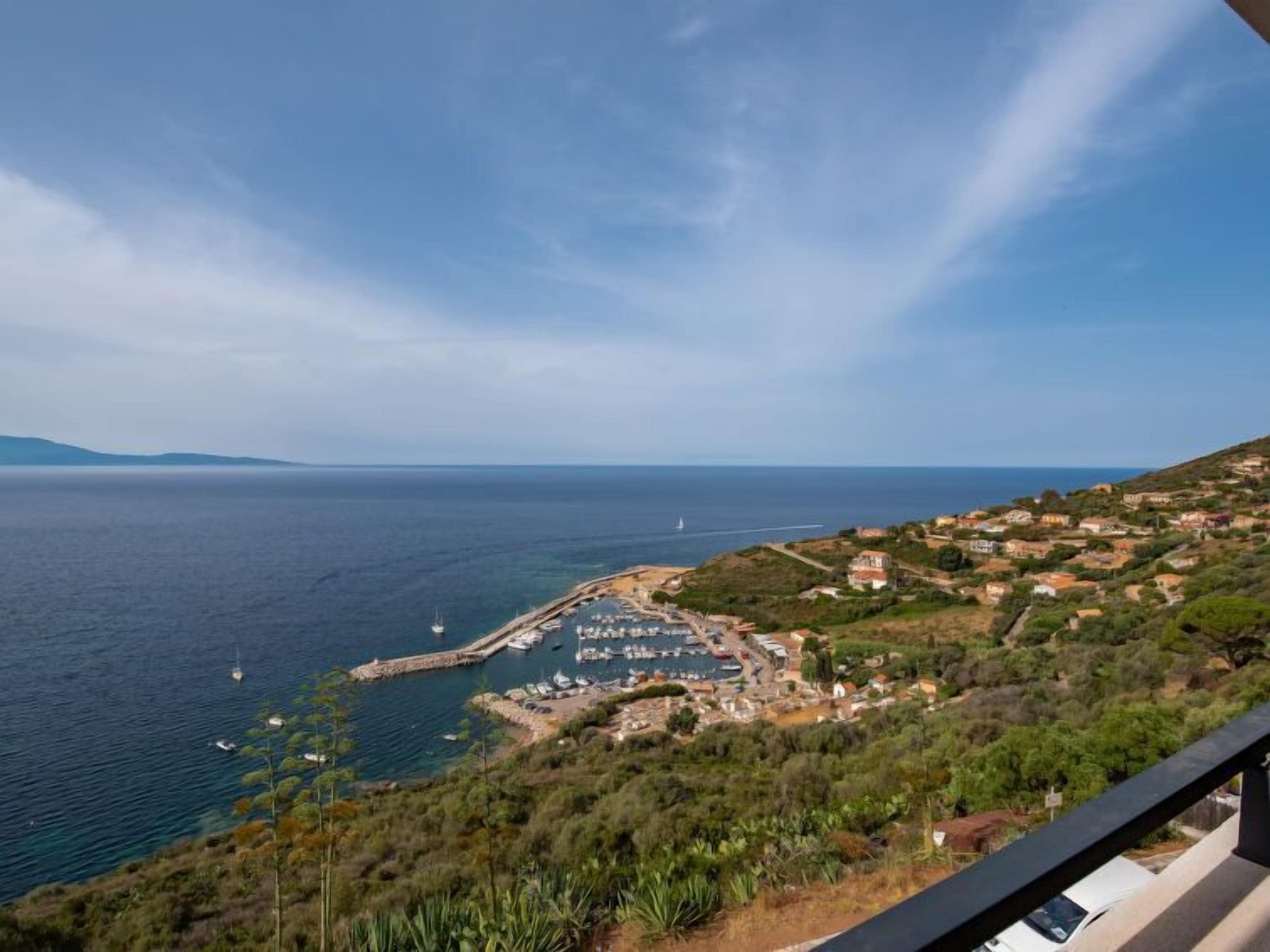 A coastal town with a marina, houses, and a clear view of the sea.
