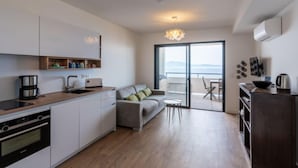 A modern kitchen with a built-in oven, a coffee maker, and a dining area with a sofa and table. - La Spelunca by Interhome (Cargèse)