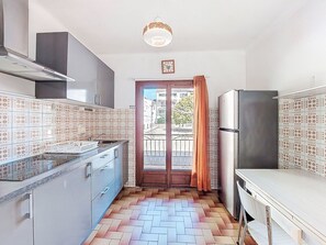 A kitchen with patterned tiles, a stainless steel refrigerator, and a herringbone floor.
