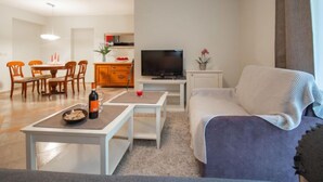 Ein modernes Wohnzimmer mit Essbereich, einem Flachbildfernseher und einer Couch.