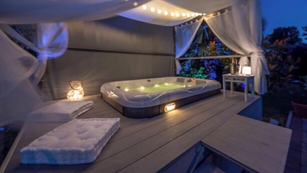 Ein Whirlpoolbereich mit Baldachin, einem Tisch mit Lampe und einer Matratze auf der Terrasse.