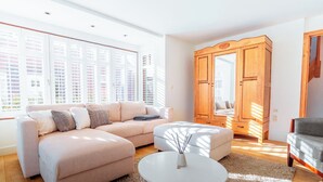 Ein modernes Wohnzimmer mit einer Couch, einem Hocker und einem Holzschrank.