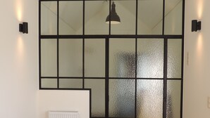Ein Schlafzimmer mit schrägem Dach, einem Heizkörper, einem Bett mit Holz-Kopfteil und einer hängenden Leuchte.