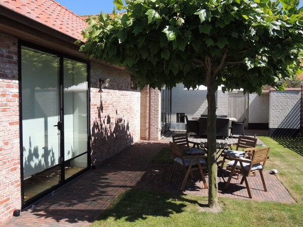 Un patio con suelo de ladrillo, una mesa de madera y sillas.