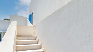 Una escalera blanca que conduce a una puerta azul, rodeada de paredes blancas.