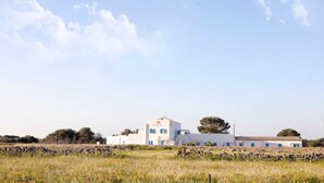 A white building with a flat roof, a small tower, and a sign with a logo. - Beach Home in Favignana with Pool (Favignana TP)