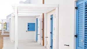 A row of white buildings with blue doors and shutters, suggesting a coastal or Mediterranean setting. - Beach Home in Favignana with Pool (Favignana TP)
