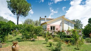 A house with a garden, a large tree, and a white fence.