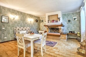 Un coin repas chaleureux avec une table et des chaises en bois, une cheminée et une bibliothèque.