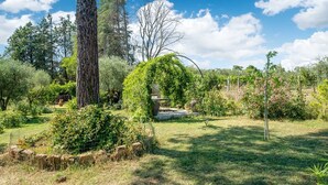 A garden with a stone bench, a tree, and a fence.