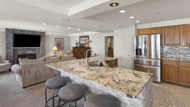 A modern kitchen with granite countertops, stainless steel appliances, and a stone fireplace. - Ski-in/Out, Walk to Base Area - Torian Plum - Pool& Hot Tubs (Steamboat Springs)